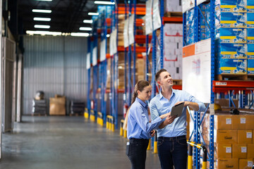 Caucasian team man and woman worker working at warehouse factory. Warehouse staff worker standing by goods shelf working in large warehouse