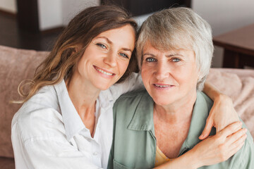 Older mature mother and grown millennial daughter laughing embracing, caring smiling young woman...