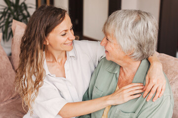 Older mature mother and grown millennial daughter laughing embracing, caring smiling young woman...