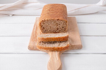 Sliced loaf of white sourdough bread on white wooden table, healthy eating
