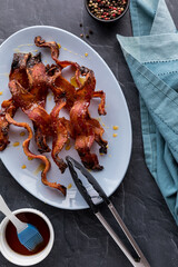 Strips of crispy peppercorn maple flavoured bacon on a platter.
