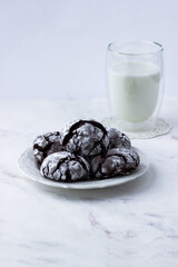 Treats on a white table. Chocolate cracks cookies and a glass of milk