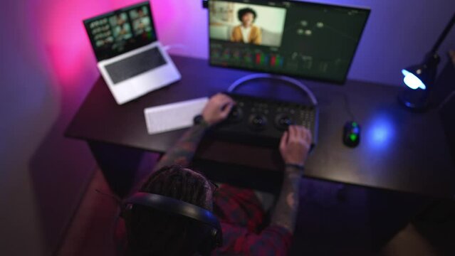 Young man in glasses working on video editing on computer doing montage and color correction. Professional man hand making edits on a special panel. Concept of creating video content.