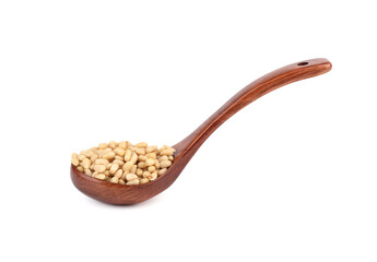 Wooden spoon with peeled pine nuts on a white background.