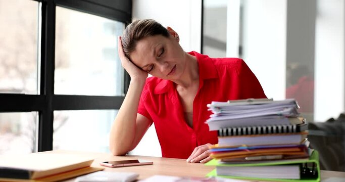 Tired sad woman with folders of documents in office. Overtime stress and depression