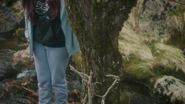Young woman walks by the river in the middle of the forest