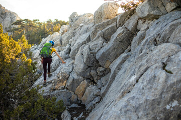 Woman climber with a backpack and a helmet in the mountains. A girl with a backpack walks along a mountain range. adventure and mountaineering concept. mountains of Turkey.