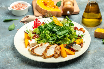 keto meal fresh salad with grilled chicken fillet, feta cheese, caramelized pumpkin, superfood concept. Healthy, clean eating, place for text, top view