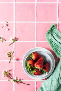 Frische Erdbeeren in einer Schüssel auf einem rosa Kachel Hintergrund. Flat lay.