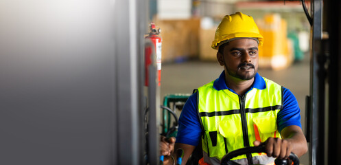 Indian man worker driving a forklift at warehouse factory. Inventory and wholesale concept. Move pallets and boxes to container
