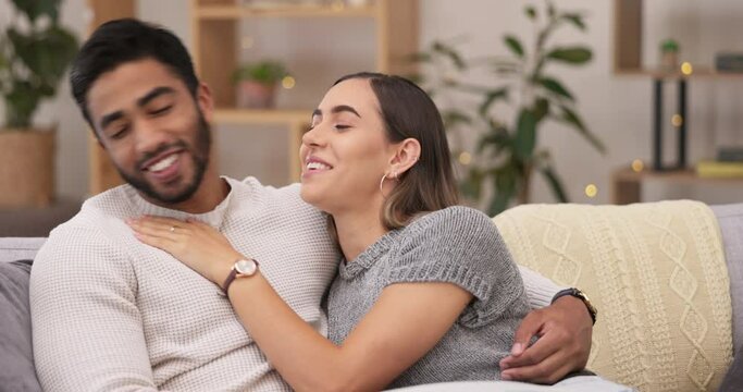 Happy, love and couple relaxing on a sofa talking, bonding and spending quality time together. Happiness, conversation and young woman kissing boyfriend on the cheek while sitting in the living room.