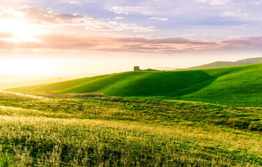 amazing sunset among green spring hills in highland farm with castle , mountains and picturesque colorful sunset on background of landscape