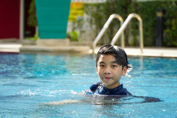 Asian boy swimming happily in the pool
