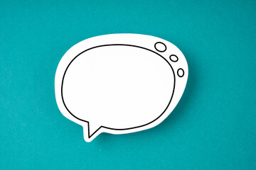The White speech bubble shaped post it note on green background with copy space.