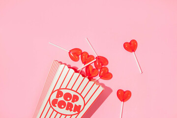 Valentines day creative layout with heart lollipops in pop corn box on pastel pink background. 80s or 90s retro fashion aesthetic love concept. Minimal romantic cosmetic idea.
