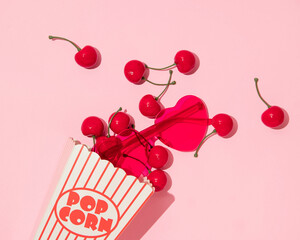Valentines day creative layout with cherries and heart sunglsses in pop corn box on pastel pink...