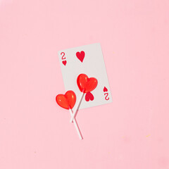 Valentines day creative layout with heart lollipops and playing card on pastel pink background. 80s...