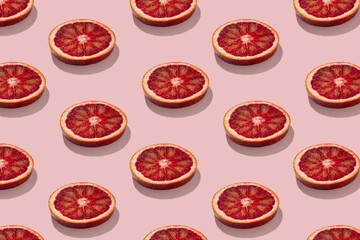 trendy seamless flat lay pattern of juicy red orange or grapefruit slices on pastel pink background minimalist summer concept