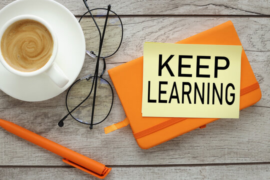 Keep Learning, ttext on yellow sticky note and desk with orange notepad