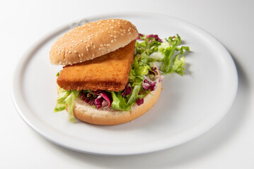Filet-O-Fish burger, breaded cod sandwich
cheddar cheese, lettuce and radicchio salad, close-up food photography on white table with subject in center , natural light and horizontal format 