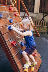 a little girl plays on the playground and rides a slide