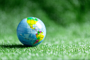 Fototapeta na wymiar Close up of blue globe on green grass on green blur nature background, earth day or world environment day concept. Green world and sustainable conservation of forest resources.