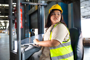 Asian fat female warehouse worker drive forklift in warehouse. Warehouse staff worker by goods shelf working in large warehouse factory