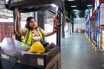 Asian fat female warehouse worker drive forklift in warehouse. Warehouse staff worker by goods...