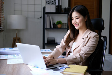 Businesswoman accountant in an accounting firm working with financial audits and budgeting using a calculator and laptop.