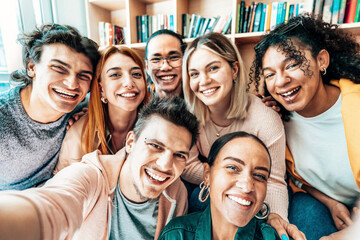Group of friends taking selfie smiling at camera in library - Happy young students in college...