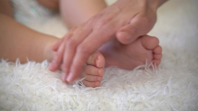 mother carefully applying medical ointment on her baby. Mother applying body cream onto feet of her little baby