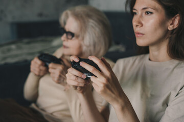 Two women playing console tv games, holding the joystick sitting on the floor in living room....
