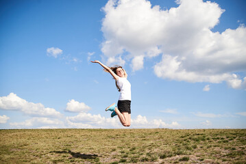 Young woman jumping on top of the mountain. Feeling happy and free. Natural landscape in summer. Sunny rural scenery. Nature protection concept. Breathtaking mountain view.. On top of the world