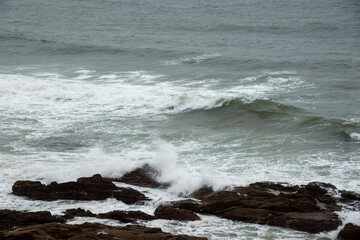wave breaking on rocks in the sea on a stormy spring day