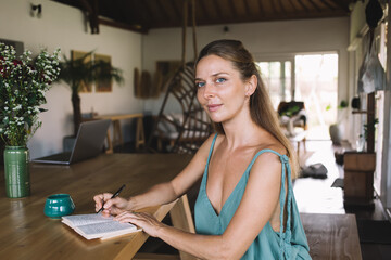 Smiling woman sitting with notebook and coffee mug at table