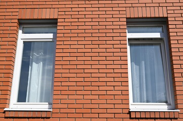 Two rectangular windows in a brick house are a structural element.