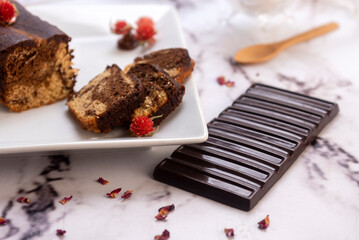 Rectangular marbled vanilla and chocolate pudding cupcakes with a chocolate bar and decorated with dried flowers and dusted with powdered sugar