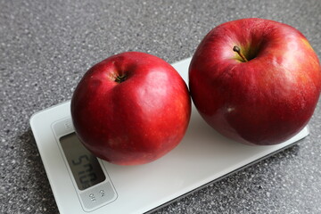 Red apples are placed on electronic scales. Electronic scales and apples on the table.