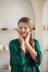 An attractive woman applies a rejuvenating and moisturizing cream to her face. Skin care. 