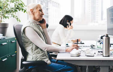 Obraz premium Concentrated multiracial colleagues sitting at tables and attending calls