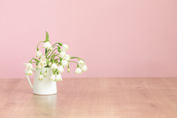white spring flowers in jug on pink background