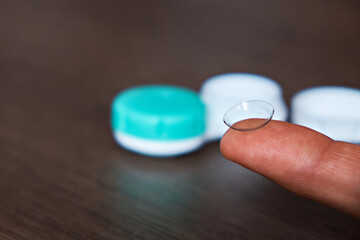 A man holds contact lenses on his finger before putting them in a container. The topic of medicine and health care. Close-up