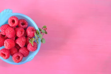 Fototapeten fresh raspberry in blue bowl,on colored background, negative space technique, free copy space © Kirsten Hinte