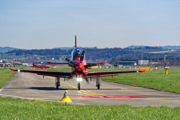 Two red and white Pilatus PC-21 propeller airplanes taxiing to runway at Swiss Air Force airbase...