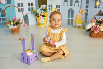 Obraz na płótnie Canvas Baby girl celebrate Easter. Funny happy kid playing on Easter egg hunt. Family home decoration, colorful Easter eggs and flowers. Home decoration and flowers