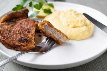 Italian breaded pork chop with parmesan cheese. Served with fresh polenta on a plate