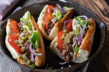 Beef Meatball sandwich with cheese, tomatoes, pickles, red onions,  and lettuce on toasted baguette bread