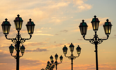A lot of vintage street lamps against dusk sky in a sea harbour