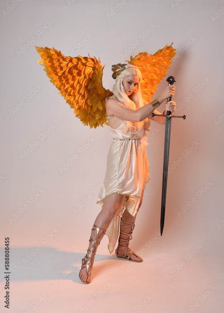 Wall mural full length portrait of beautiful blonde woman wearing a fantasy goddess toga costume with feathered