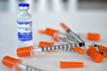 A vial of insulin medicine with a needle or syringe for injections.
